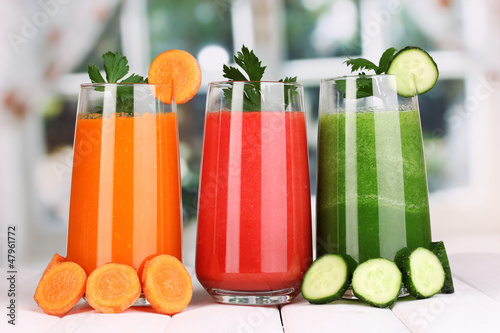 Photo: Fresh vegetable juices on wooden table, on window background Fresh vegetable juices on wooden table, on window background