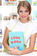 A young girl in kitchen with cookbook