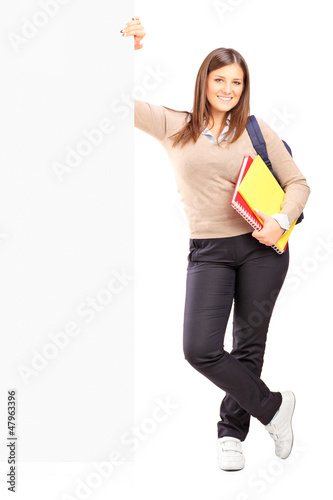Photo: Smiling female student standing next to a billboard Smiling female student standing next to a billboard