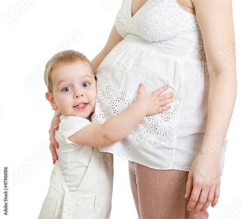 Photo: Little boy hugging pregnant mother's belly and looking directly Little boy hugging pregnant mother's belly and looking directly