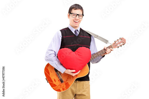 Photo: Romantic young man playing an acoustic guitar and holding a red Romantic young man playing an acoustic guitar and holding a red