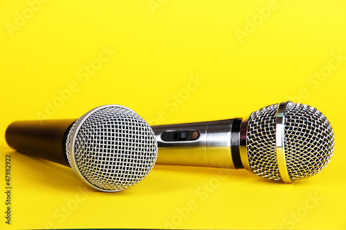 Photo: Silver and black microphones on yellow background Silver and black microphones on yellow background