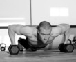 Foto: Gym man push-up strength pushup with dumbbell Gym man push-up strength pushup with dumbbell