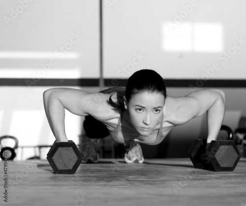 Photo: Gym woman push-up strength pushup with dumbbell Gym woman push-up strength pushup with dumbbell