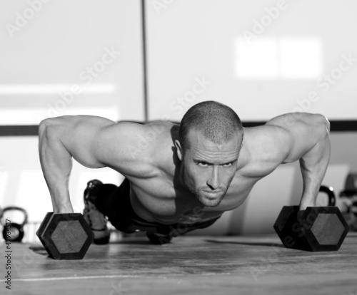 Photo: Gym man push-up strength pushup with dumbbell Gym man push-up strength pushup with dumbbell