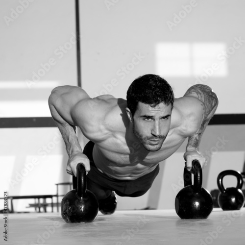Photo: Gym man push-up strength pushup with Kettlebell Gym man push-up strength pushup with Kettlebell