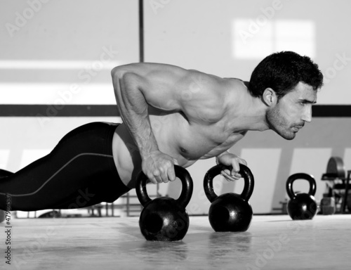 Photo: Gym man push-up strength pushup with Kettlebell Gym man push-up strength pushup with Kettlebell