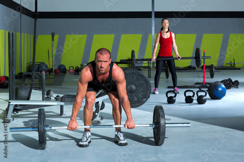 Photo: gym with weight lifting bar workout man and woman gym with weight lifting bar workout man and woman