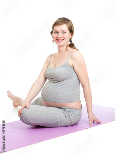 Photo: Pregnant woman doing gymnastic exercises isolated on white Pregnant woman doing gymnastic exercises isolated on white
