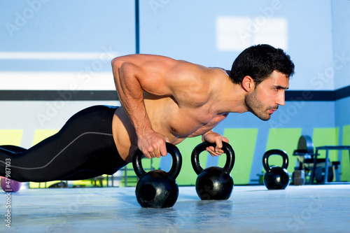 Photo: Gym man push-up strength pushup with Kettlebell Gym man push-up strength pushup with Kettlebell