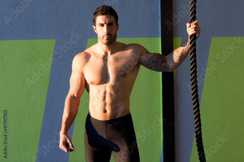 Photo: Crossfit gym man holding hand a climbing rope Crossfit gym man holding hand a climbing rope