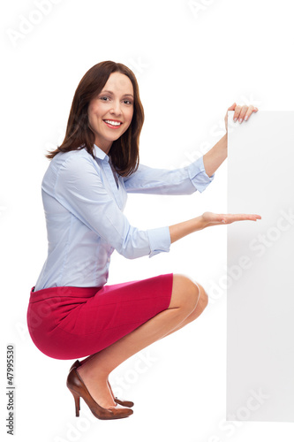 Photo: Businesswoman crouching by blank board Businesswoman crouching by blank board