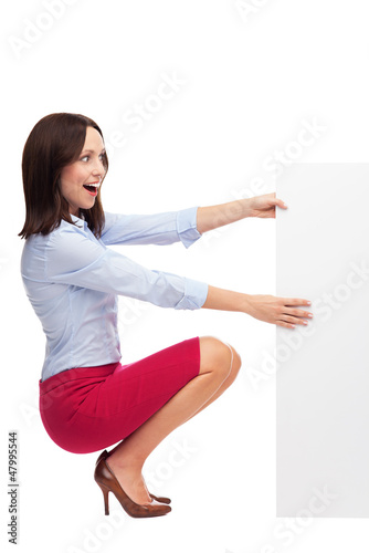 Photo: Businesswoman crouching by blank board Businesswoman crouching by blank board