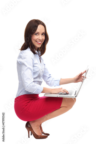 Photo: Businesswoman crouching with laptop Businesswoman crouching with laptop