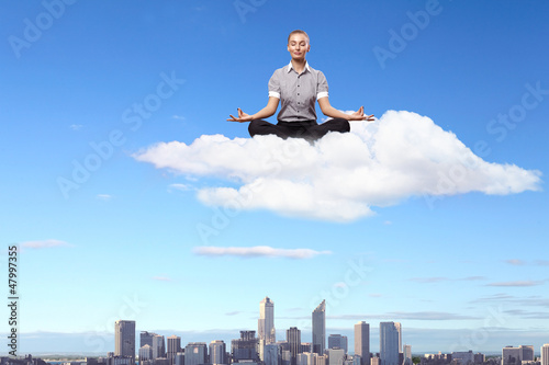 Photo: Businesswoman meditating sitting on the cloud Businesswoman meditating sitting on the cloud