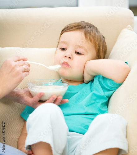 Photo: Cute little boy is fed using spoon Cute little boy is fed using spoon