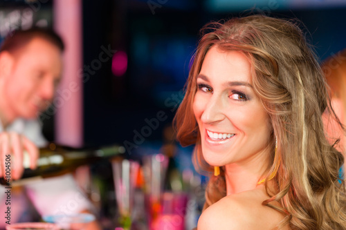 Photo: Young woman in club or bar drinking champagne Young woman in club or bar drinking champagne