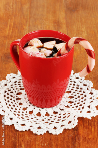 Photo: Cup of coffee with holiday candy on wooden table close-up Cup of coffee with holiday candy on wooden table close-up