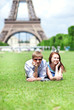 Closeup of happy positive couple laying on the grass near the Ei