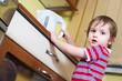 Little baby boy is reaching eletrical kettle with hot water
