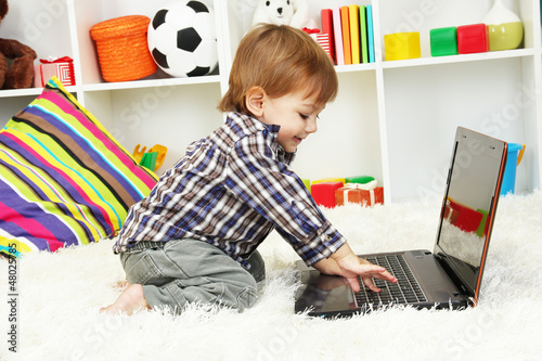 Photo: cute little boy and notebook in room cute little boy and notebook in room