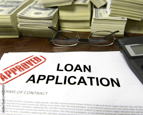 Photo: Approved loan application form and dollar bills Approved loan application form and dollar bills