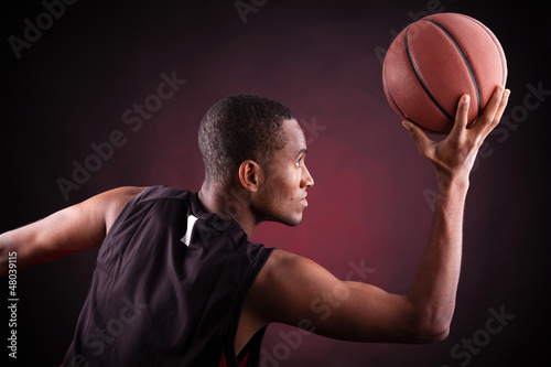 Photo: young male basketball player against black background young male basketball player against black background