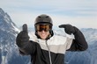 Skifahrer deutet auf Helm mit Daumen hoch im Skigebiet