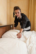 Chambermaid woman changing sheets in a hotel room.