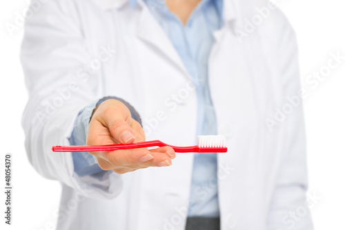 Photo: Closeup on toothbrush in hands of medical dental doctor Closeup on toothbrush in hands of medical dental doctor