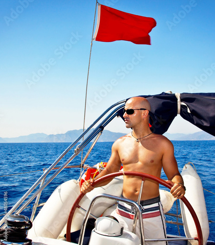 Photo: Man at the helm of yacht Man at the helm of yacht
