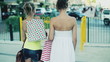 Happy young female friends walking with shopping bags in the cit