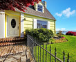 Yellow small home with water view and red maple.