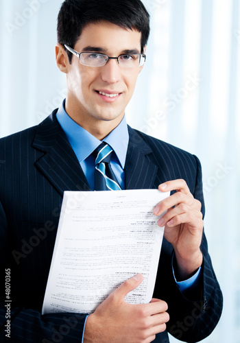 Photo: Businessman with document or contract, at office Businessman with document or contract, at office