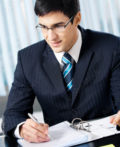 Photo: Portrait of writing smiling businessman working at office Portrait of writing smiling businessman working at office