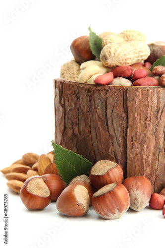 Photo: assortment of tasty nuts with leaves in wooden vase, isolated assortment of tasty nuts with leaves in wooden vase, isolated