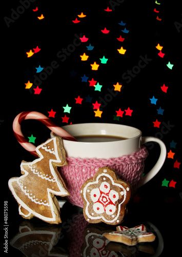 Photo: Cup of coffee with holiday candy on Christmas lights background Cup of coffee with holiday candy on Christmas lights background