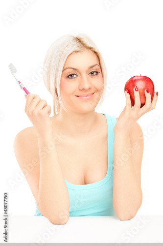 Photo: Beautiful blond woman holding red apple and tooth brush Beautiful blond woman holding red apple and tooth brush