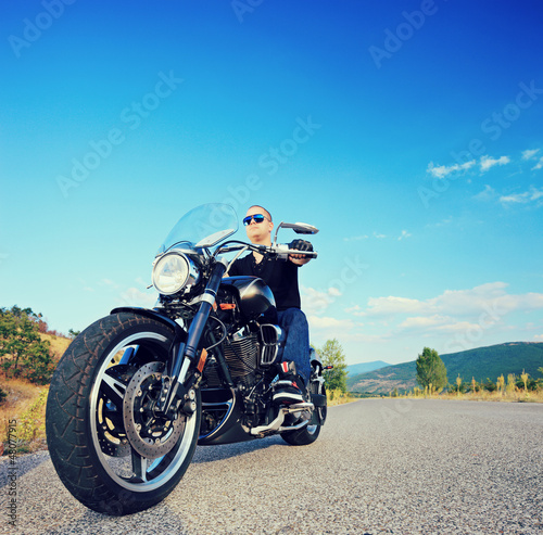 Photo: Biker riding a customized motorcycle on an open road Biker riding a customized motorcycle on an open road
