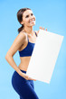 Woman in fitnesswear showing signboard, over blue