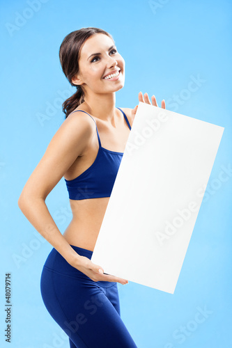 Photo: Woman in fitnesswear showing signboard, over blue Woman in fitnesswear showing signboard, over blue