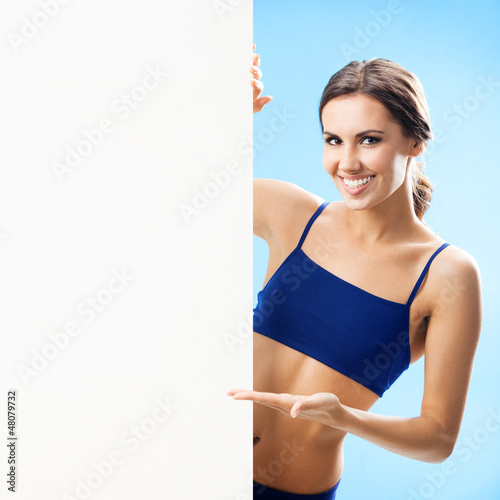 Photo: Woman in fitnesswear showing signboard, over blue Woman in fitnesswear showing signboard, over blue