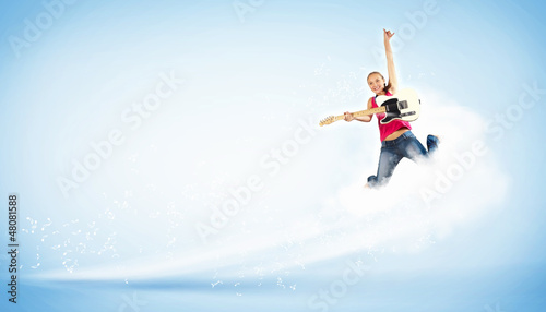 Photo: young woman playing on electro guitar and jumping young woman playing on electro guitar and jumping