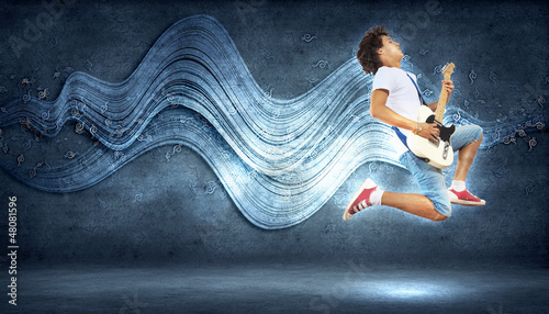 Photo: young man playing on electro guitar and jumping young man playing on electro guitar and jumping