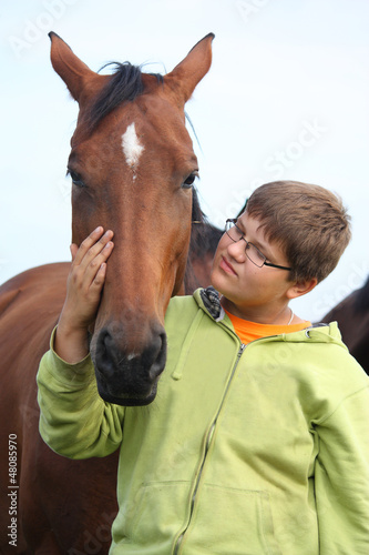 Photo: Smiling teenager boy with horses at the field Smiling teenager boy with horses at the field