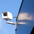 Security camera reflected on shiny building facade