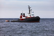 Tugboat floating in wait on calm ocean at anchor