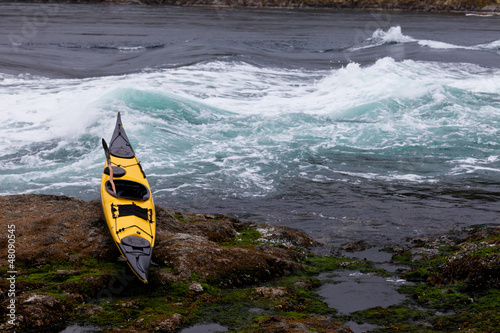 Photo: Ocean kayak beached on rocky shore at tidal rapids Ocean kayak beached on rocky shore at tidal rapids
