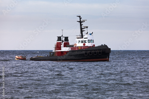 Photo: Tugboat floating in wait on calm ocean at anchor Tugboat floating in wait on calm ocean at anchor