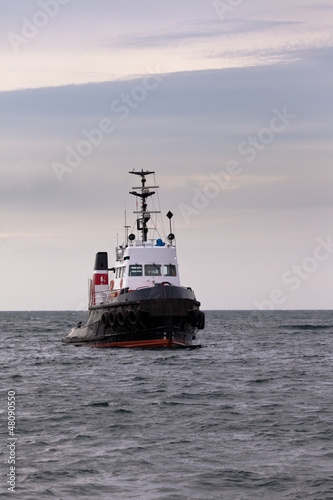 Photo: Tugboat floating in wait on calm ocean at anchor Tugboat floating in wait on calm ocean at anchor